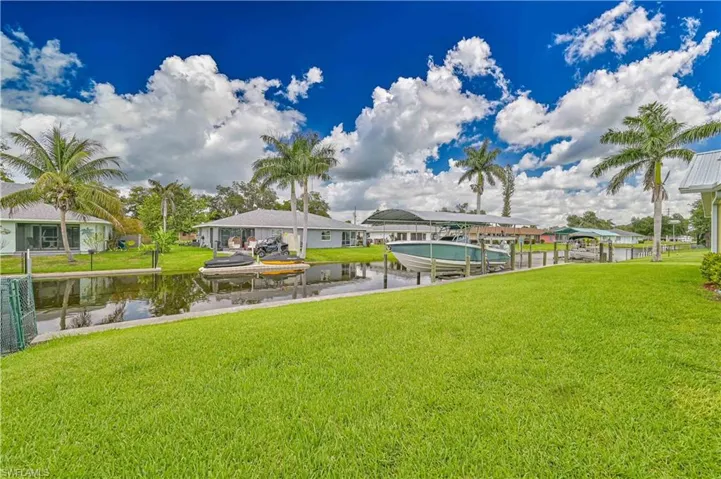 Waterfront property featuring a canal, private dock, and covered boat lift