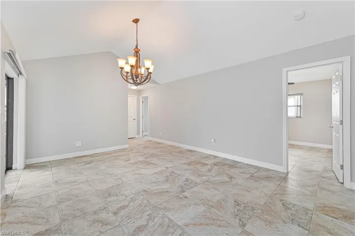 Spacious room featuring vaulted ceilings, neutral wall paint, and large format tiled flooring