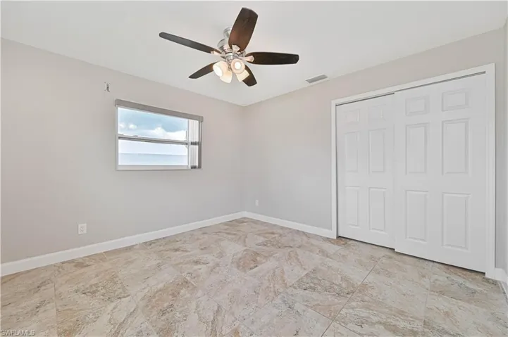 Room featuring large format multi-tone tile flooring, neutral wall tones, and a window with water scenery