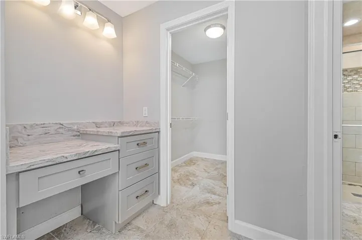 Built-in vanity with light grey cabinetry and stone countertops