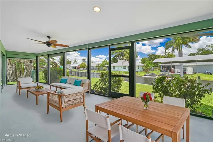 Spacious screened lanai featuring a ceiling fan, recessed lighting, and expansive views of the adjacent canal