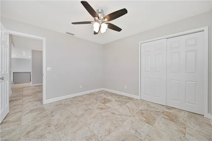 Room featuring large-format tile flooring, a ceiling fan with integrated lighting, and a bi-fold closet with paneled doors