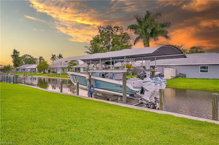 Waterfront property featuring a canal, private dock with a boat lift, and a covered boat canopy