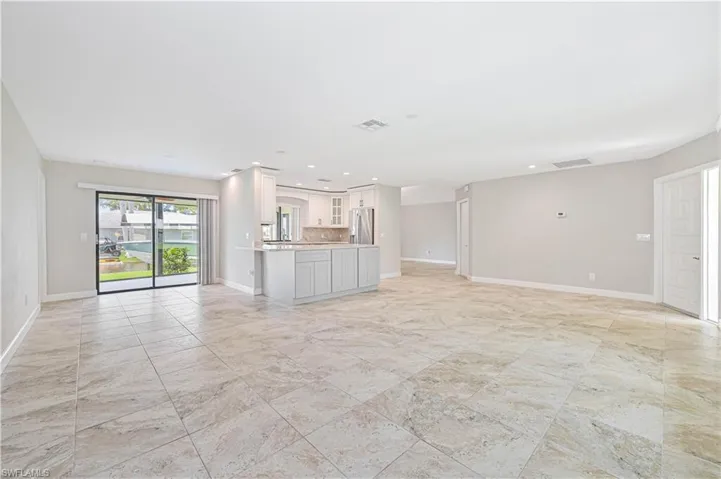 Open-concept living space featuring large format tile flooring, light neutral wall paint, and recessed lighting