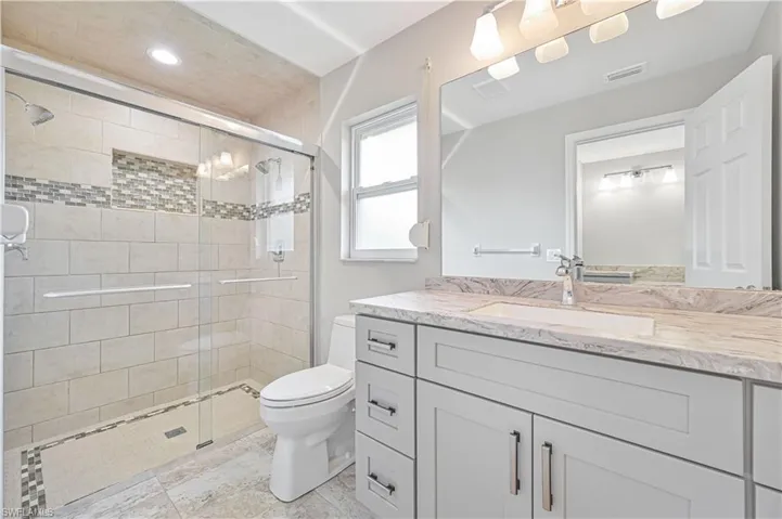 Bathroom featuring a glass-enclosed shower with subway tile, mosaic accent band, and recessed niche