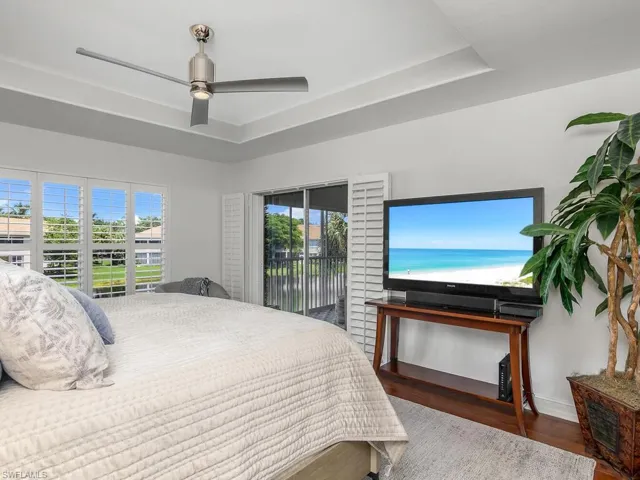 Bedroom with a raised ceiling, hardwood floors, and multiple windows