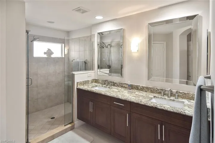 Master bath with double vanity, a shower stall, and recessed lighting