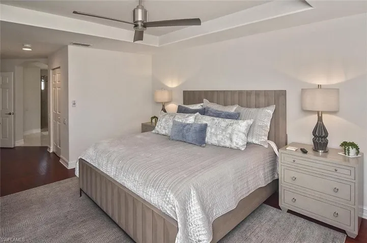 Bedroom featuring a raised ceiling, hardwood floors, a closet, arched walkways, and a ceiling fan