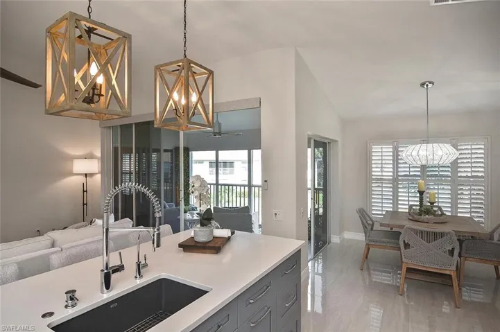 Kitchen featuring a chandelier, decorative light fixtures, gray cabinets, plenty of natural light, and lofted ceiling