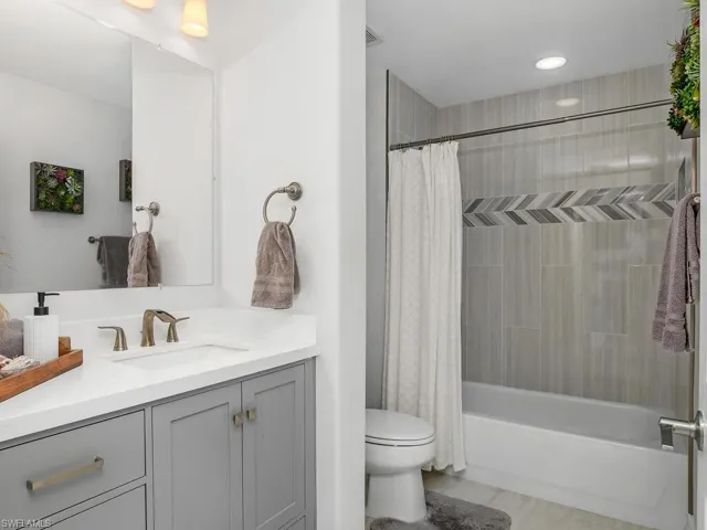 Guest Bathroom featuring Porcelain floors, vanity and shower / bath combo with shower curtain