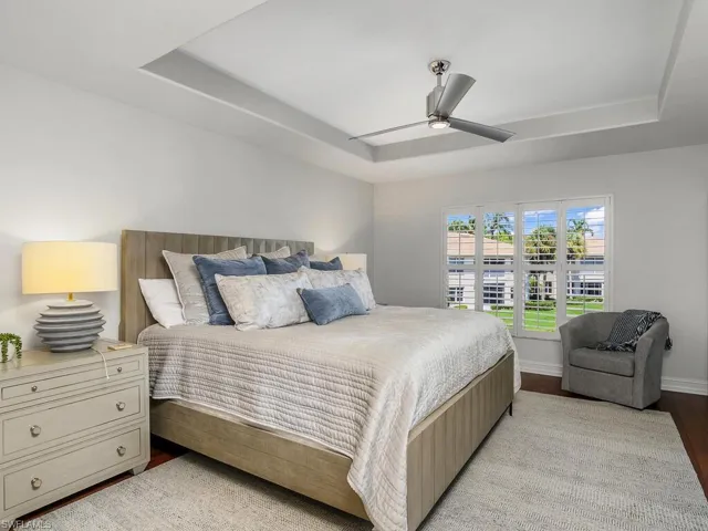 Master Bedroom with a raised ceiling, hardwood floors, and a ceiling fan