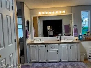 Bathroom featuring double vanity and a textured ceiling