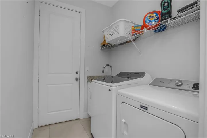The laundry room features a modern washing machine and dryer, a utility sink with a granite-style countertop, and a wire shelf for storage