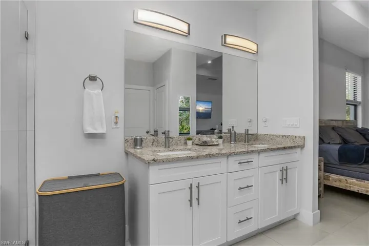 Bathroom featuring a double vanity with white cabinetry, granite countertops, and two vessel sinks, illuminated by two modern light fixtures