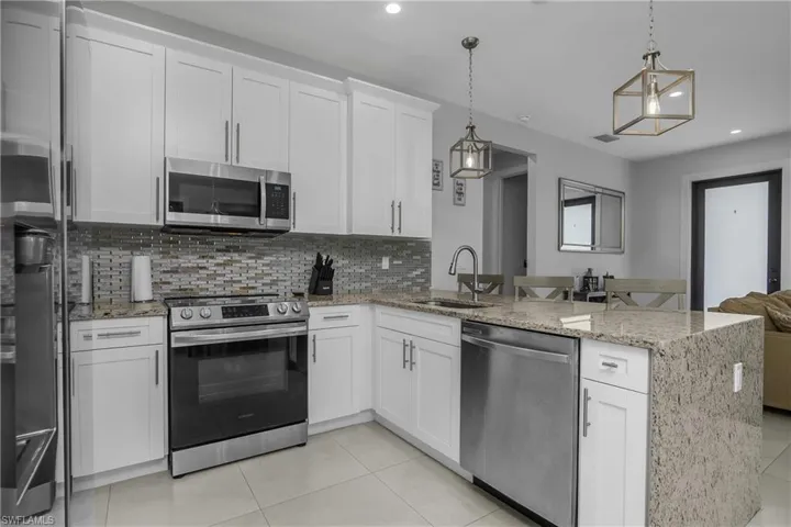 The kitchen features white cabinetry, stainless steel appliances, and granite countertops