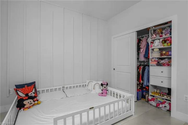 This room features a white board and batten accent wall, light-colored flooring, and a built-in closet with sliding doors