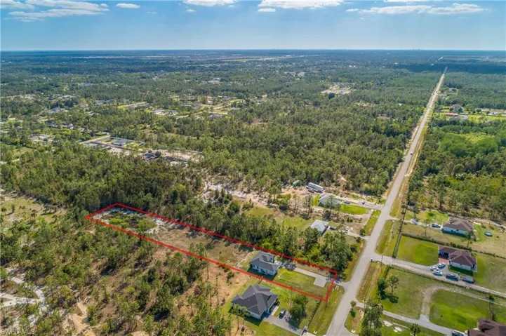 Aerial view of a property with a distinct perimeter indicated by a red outline, set within an expansive area of dense trees