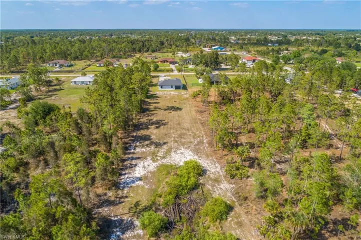 The property features extensive land with a mix of natural vegetation and cleared areas, surrounded by mature trees