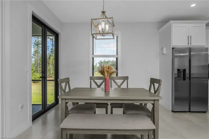 Dining area with light-toned flooring, a window with blinds, and French doors leading to an outdoor space with natural views