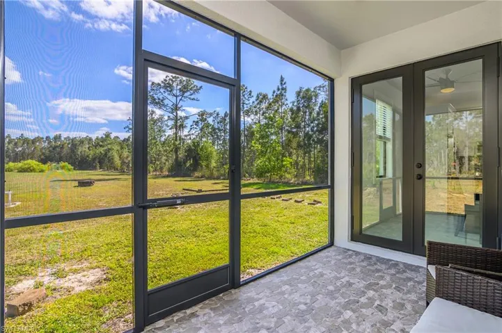 Screened-in patio with tiled flooring provides views of the extensive grassy yard and mature trees