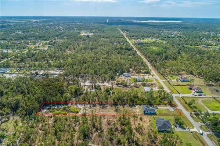 Aerial view of the property, outlined in red, featuring extensive undeveloped land with mature trees