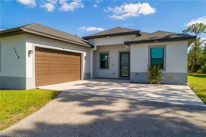 The property features a spacious driveway and an integrated garage with a brown panel door