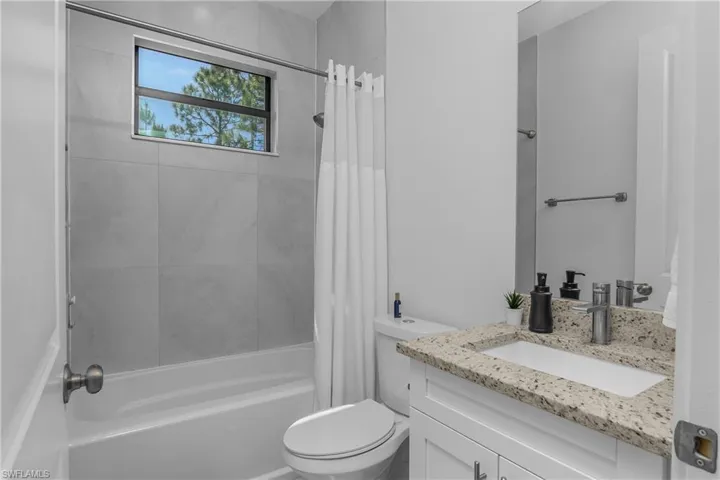 Bathroom featuring a white vanity with a granite countertop and an undermount sink