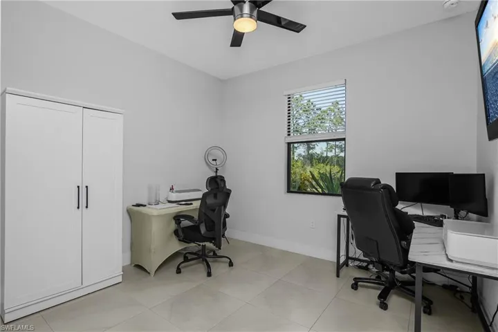 This room features light-colored walls and floor tiles, a window with blinds providing natural light, and a ceiling fan with integrated lighting