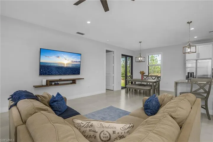 This open-concept living space features light-colored tile flooring and recessed lighting