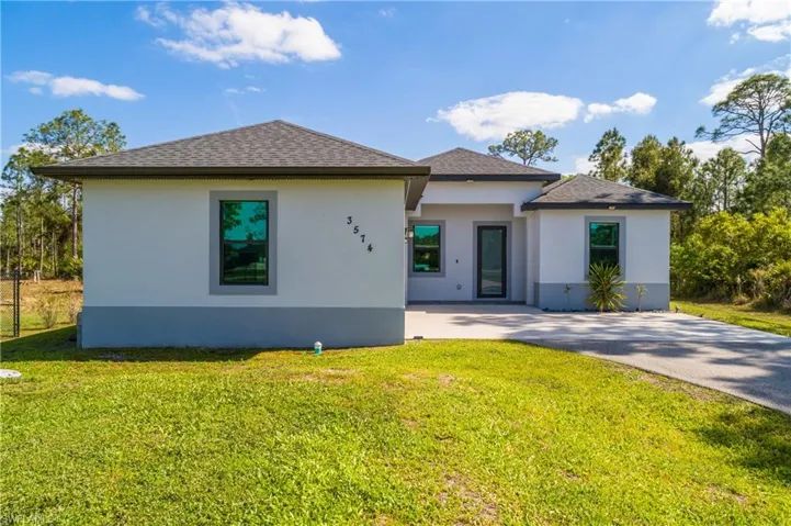 The property features a well-maintained lawn and a paved driveway leading to the entrance