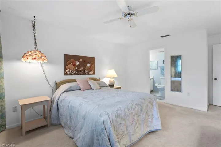 Bedroom with a ceiling fan, light colored carpet, and ensuite bathroom