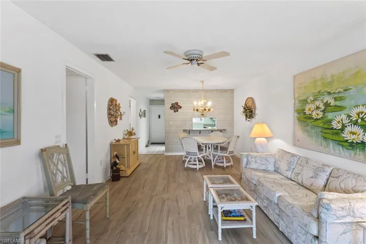 Living room with wood finished floors, a ceiling fan, and suspended lighting