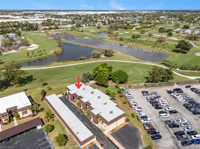 Aerial view of property and surrounding area featuring a golf club and nearby suburban area