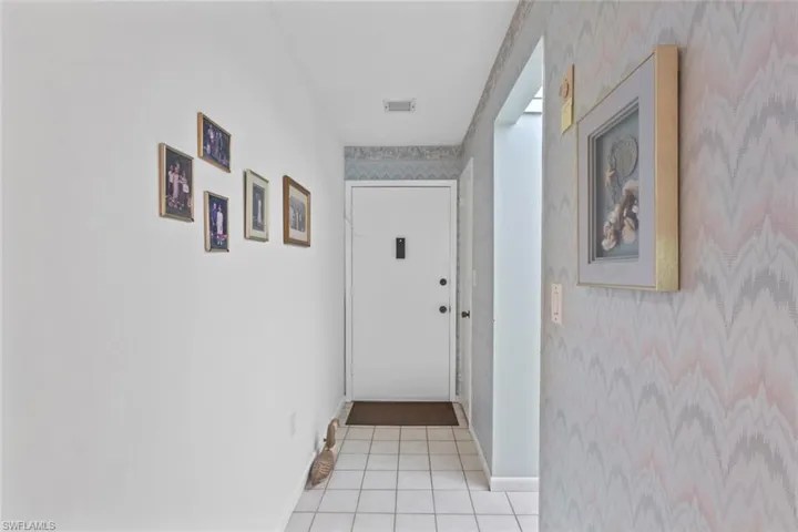 Corridor featuring wallpapered walls and light tile patterned floors