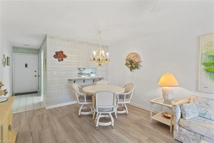 Dining area featuring light wood-style flooring, a chandelier, and wallpapered walls