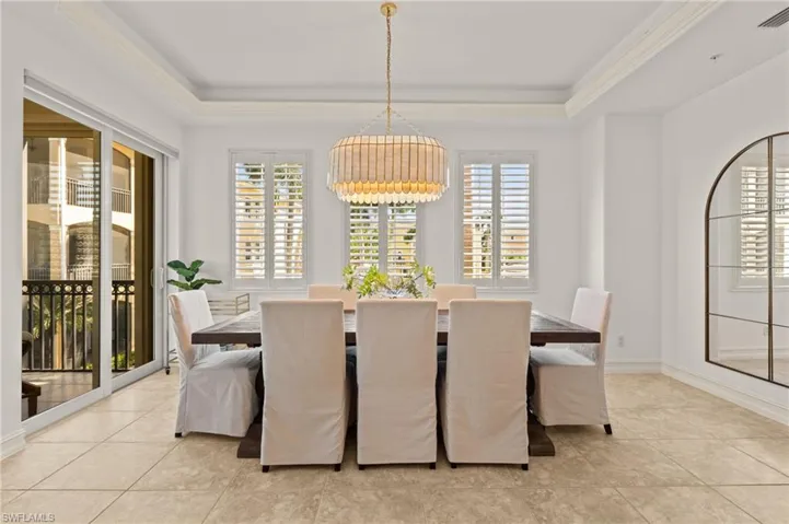 Dining area with a healthy amount of sunlight, a chandelier, and a raised ceiling