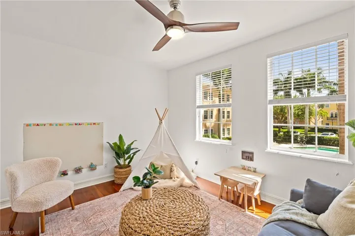 Living area with baseboards, wood finished floors, ceiling fan, and a healthy amount of sunlight
