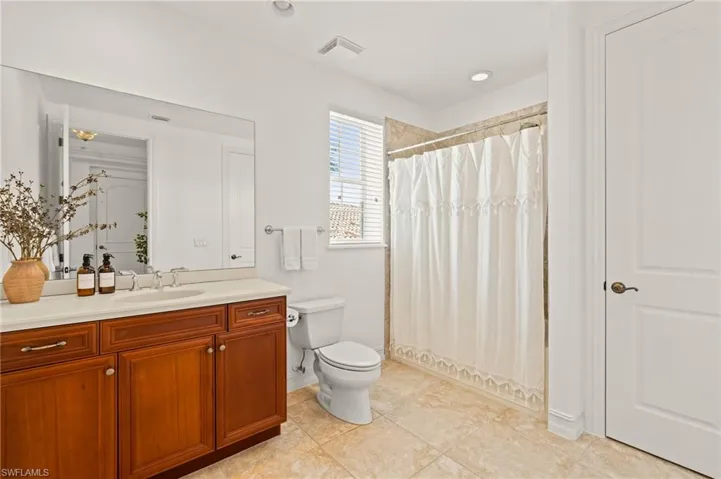 Full bathroom with baseboards, toilet, vanity, a shower with curtain, and tile patterned flooring