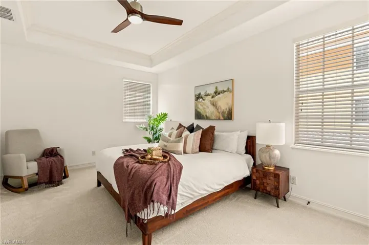 Bedroom with carpet flooring, a tray ceiling, baseboards, and crown molding