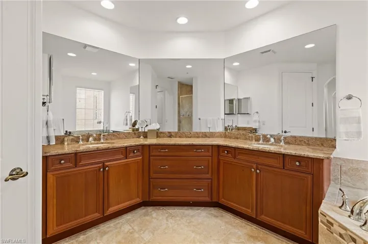 Bathroom featuring double vanity, a sink, a tile shower, and visible vents