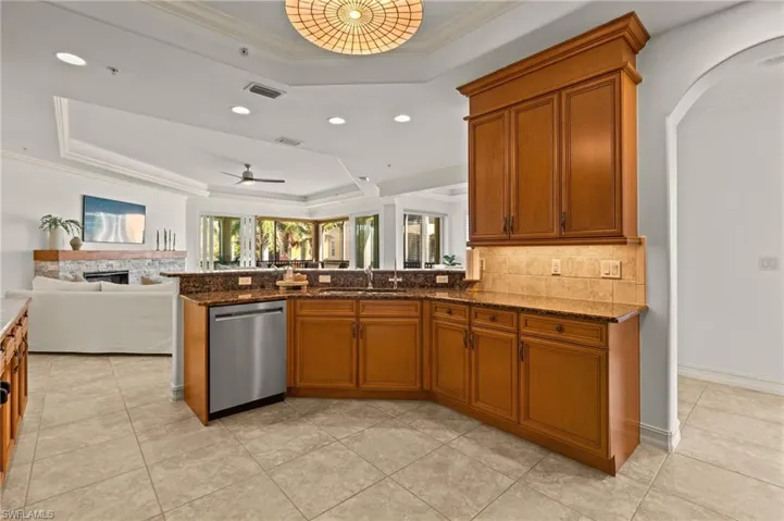Kitchen featuring a sink, a raised ceiling, dishwasher, open floor plan, and visible vents