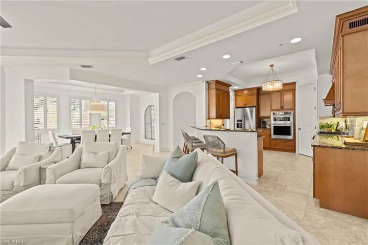 Living room with a tray ceiling, visible vents, recessed lighting, and ornamental molding