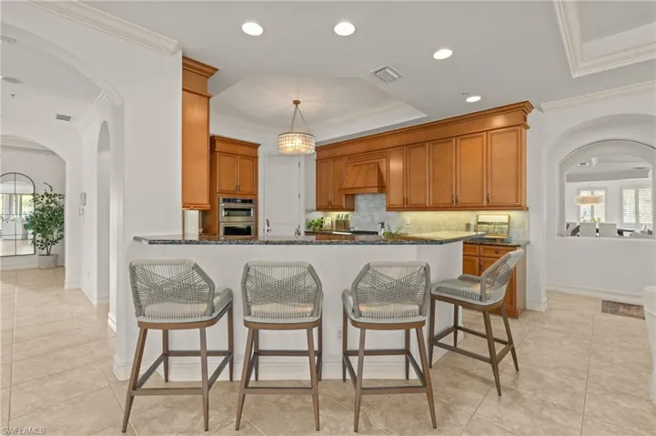Kitchen with stainless steel double oven, visible vents, brown cabinetry, and crown molding