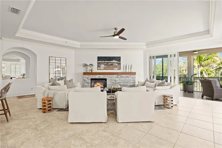 Living area with a tray ceiling, visible vents, plenty of natural light, and ceiling fan