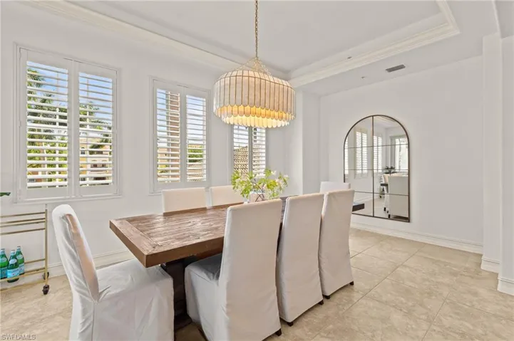 Dining room featuring a tray ceiling, crown molding, baseboards, visible vents, and an inviting chandelier