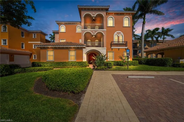 View of front of property with a tile roof, a balcony, uncovered parking, a front lawn, and ceiling fan