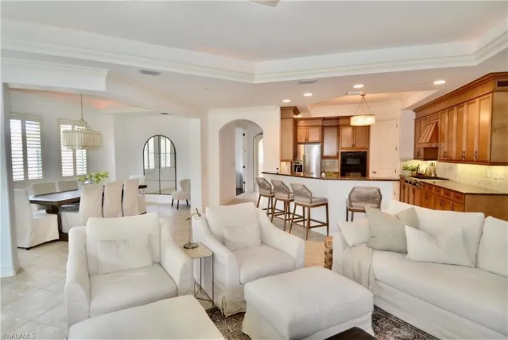 Living room with light tile patterned floors, recessed lighting, arched walkways, and a raised ceiling