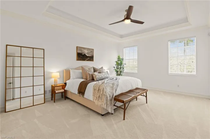 Bedroom featuring a tray ceiling, baseboards, crown molding, and carpet