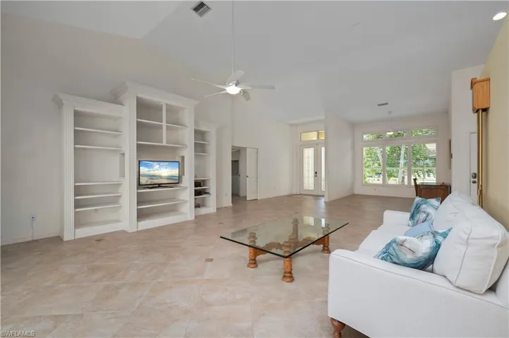 Unfurnished living room featuring lofted ceiling, ceiling fan, and light tile patterned floors