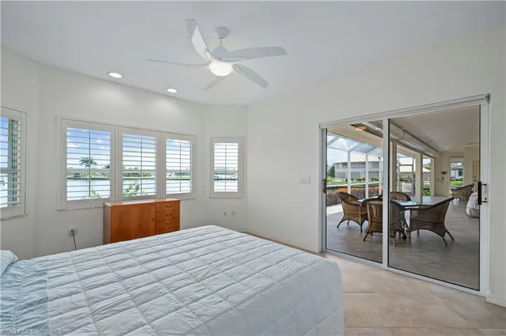 Tiled bedroom with a water view, ceiling fan, and access to exterior